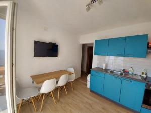 a kitchen with blue cabinets and a table and chairs at Frane Apartment in Zavalatica +39 photos