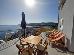 una terrazza con sedie, tavolo e ombrellone di Frane Apartment a Zavalatica