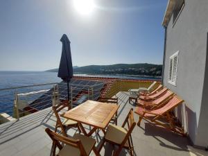 a deck with chairs and a table and an umbrella at Frane Apartment in Zavalatica