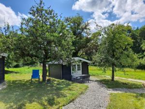 a small shed with a blue chair in a yard at Camping Weides in Küps