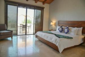 a bedroom with a bed and a chair and a balcony at La Reserva Chapala in Ajijic
