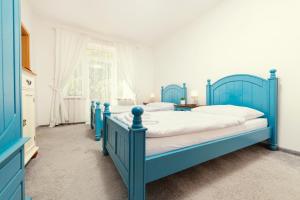 1 dormitorio azul con 2 camas y ventana en Hotel Ostende en Chocerady