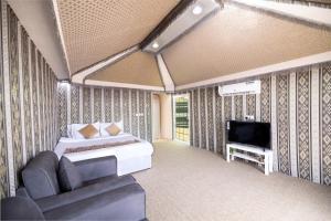 a bedroom with a bed and a tv and a couch at منتجع قرية الفقرة in As Sudayrah