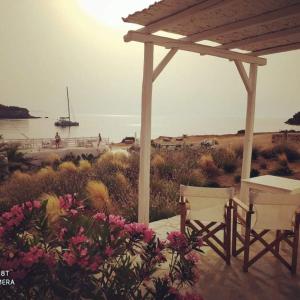 a patio with a gazebo and two chairs and flowers at Sunset Studios & Rooms in Antiparos