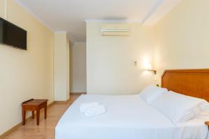 a bedroom with a white bed and a flat screen tv at Hotel Residencial Colibri in Costa da Caparica +37 photos