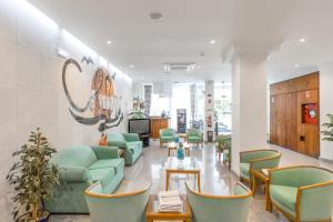 a waiting room with green chairs and a table at Hotel Residencial Colibri in Costa da Caparica