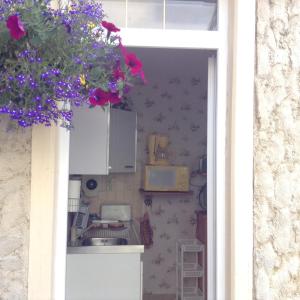 a kitchen through a window with flowers hanging from it at Au Bon Gite - Studio in Arromanches-les-Bains