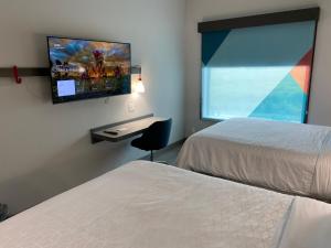 a hotel room with two beds and a flat screen tv at AVID Hotels Corpus Christi - Portland, an IHG Hotel in Portland