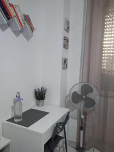 Cette chambre blanche dispose d'un bureau et d'un ventilateur. dans l'établissement Sa Sindria, à Cagliari