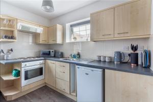 a kitchen with wooden cabinets and a counter top at Guest Homes - New Street Accommodation in Worcester