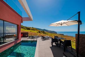 een huis met een zwembad en een parasol bij OurMadeira - Villa Tranquility, peaceful in Calheta