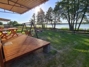 a deck with a swing and a picnic table at Siedlisko nr 4E i 4F nad jeziorem Skarlińskim, jezioro, mazury, domki letniskowe, bania in Kurzętnik