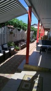 a patio with red columns and benches and a fence at Vila Masco in Costinesti