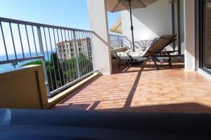 - un balcon avec un parasol, une table et des chaises dans l'établissement Studio avec splendide vue sur mer, au Lavandou