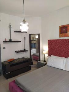 レトイアンニにあるCastagna Apartment Letojanni - Taorminaのベッドルーム1室(赤いヘッドボードと鏡付きのベッド1台付)