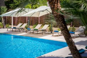 a group of chairs and umbrellas next to a pool at Hotel Torino Wellness & Spa in Diano Marina