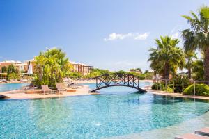 a bridge over a pool at a resort with palm trees at Monte Santo Resort in Carvoeiro