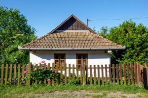 une petite maison blanche derrière une clôture en bois dans l'établissement Lóci Palócház, à Nagylóc