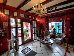 una sala de estar con paredes y sillas rojas y una lámpara de araña. en Hotel Boutique Casona Maya Mexicana, en Tapachula