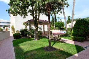 a garden with palm trees and a gazebo at Apartamento Golf Pau Casals in Albir