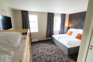 una camera d'albergo con due letti e due finestre di Sandnessjøen Overnatting a Sandnessjøen