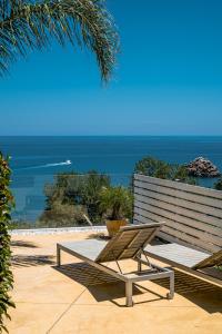 a bench and a chair on a patio with the ocean at A Tonnara in Cefalù