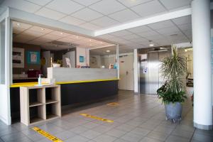 un hall de bureau avec une réception et des plantes en pot dans l'établissement Kyriad Direct Arras - Saint-Laurent-Blangy - Parc Expo, à Saint-Laurent-Blangy