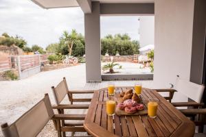 a wooden table with a plate of food and orange juice at Poseidon close to the beach in Agios Nikolaos