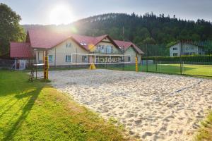 a sand volleyball court with a playground in front of a house at Promenada in Węgierska Górka