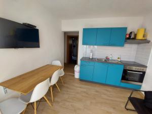 a kitchen with blue cabinets and a wooden table and chairs at Frane Apartment in Zavalatica
