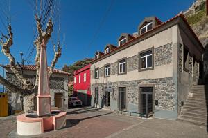 een straat met een rood gebouw en een paal bij The Rum Inn in Calheta