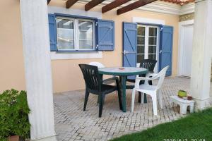 a table and chairs on a patio with blue doors at Villa Terra da Eira T1 - Sun, Sea and Relax in Lourinhã