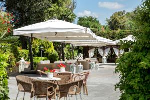 a patio with tables and chairs with umbrellas at Montespina Park Hotel in Naples