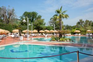 a large swimming pool with chairs and umbrellas at Montespina Park Hotel in Naples