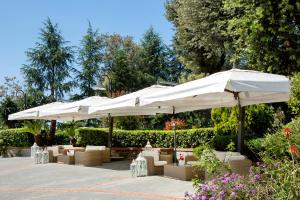 a patio with white umbrellas and tables and chairs at Montespina Park Hotel in Naples
