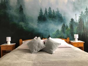 1 dormitorio con 1 cama y una pintura de un bosque en Ognisko Dom Wypoczynkowy, en Wisła
