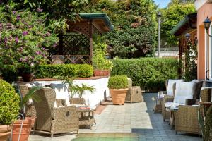 a patio with wicker chairs and tables and plants at Montespina Park Hotel in Naples