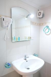 La salle de bains est pourvue d'un lavabo blanc et d'un miroir. dans l'établissement Miracle Apartments Saranda, à Saranda
