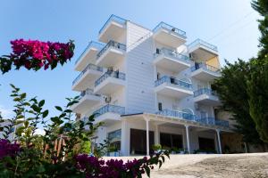 - un grand bâtiment blanc avec balcon et fleurs violettes dans l'établissement Miracle Apartments Saranda, à Saranda