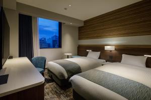 a hotel room with two beds and a window at Shizutetsu Hotel Prezio Tokyo Tamachi in Tokyo