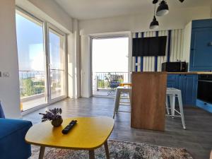 ein Wohnzimmer mit einem Tisch und eine Küche mit blauen Schränken in der Unterkunft Velier Summer Apartment in Mamaia