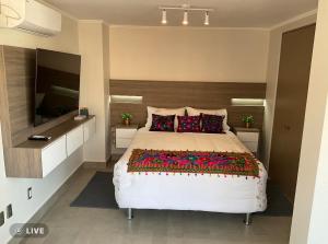 een slaapkamer met een groot bed en een tv aan de muur bij Apartament Condo Amueblado, ENCOMENDEROS 200 El Golf, Las Condes Santiago con vista al Costanera Center in Santiago