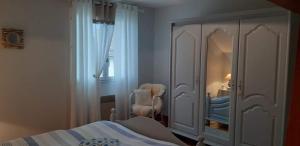 een slaapkamer met een bed, een stoel en een spiegel bij Nuit Champenoise Tout Confort in Louze
