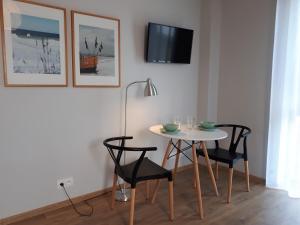 a table and chairs in a room with a tv on the wall at Sosenka in Niechorze