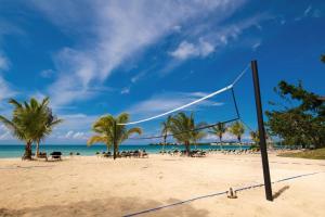 a volley ball net on a beach with palm trees at Riu Palace Tropical Bay - All Inclusive in Negril