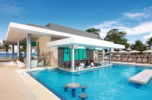 een zwembad in een resort met stoelen en een bar bij Riu Palace Tropical Bay - All Inclusive in Negril