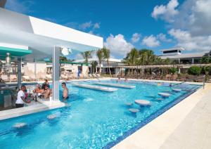 una piscina en un complejo con gente sentada en él en Riu Palace Tropical Bay - All Inclusive en Negril