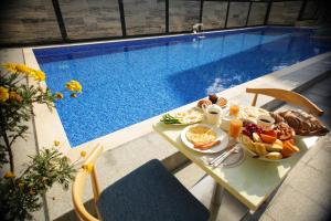 una mesa con desayuno junto a la piscina en Chveni Ezo Boutique Hotel en Kobuleti