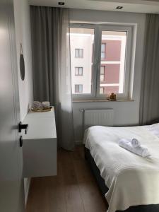 a bedroom with a white bed and a window at Apartament Avior in Iława