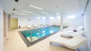 a swimming pool in a room with white chairs and a white poolvisor at Hotel Rössle Superior in Galtür